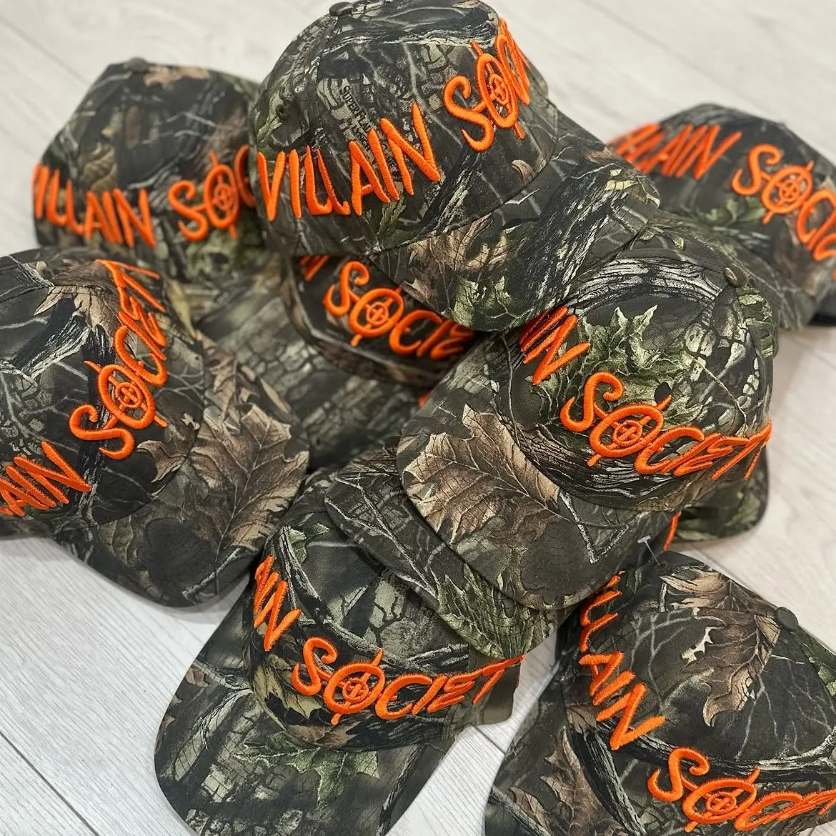 Camouflage caps with orange Villain Society embroidery